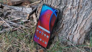 The Moto G Stylus 5G facing forward at an angle against a tree.
