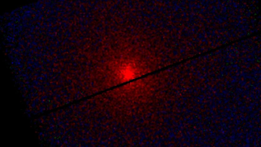 A red glowing light surrounded by black edges with cracks of black throughout the image