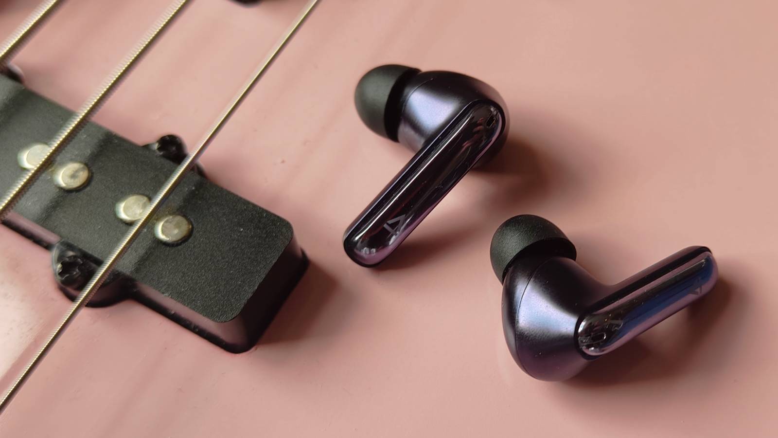 The Creative Aurvana Ace 3 buds on a pink bass guitar.