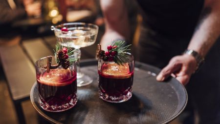 Hands holding a tray of three Christmas cocktails