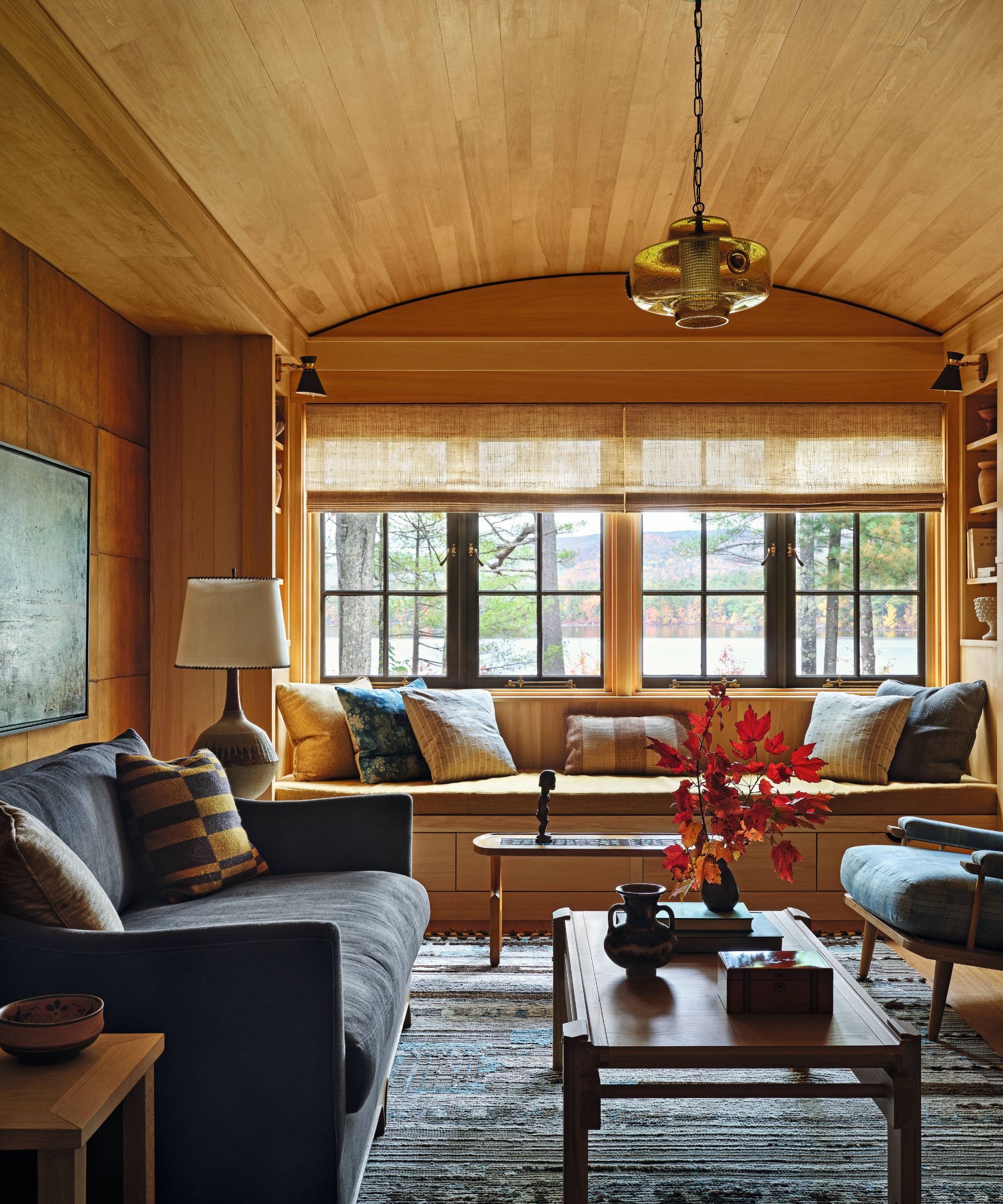 Wood panelled living room with built in window seat and dark blue sofa