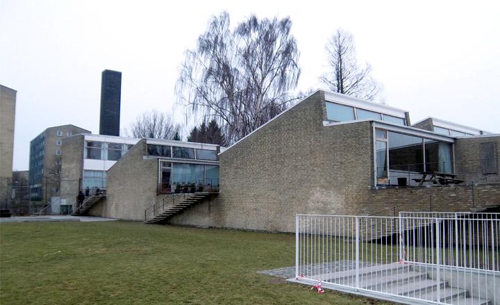 Side profile of a series of brick-built buildings with large glass frontages and architectural lines.