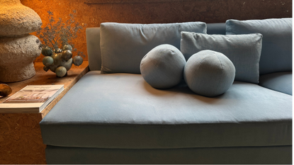 Sky blue ball pillow trio clustered atop a sleek-lined sofa with matching upholstery