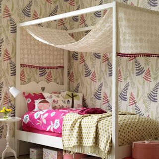summer bedroom with four poster bed and patterned bold wallpaper
