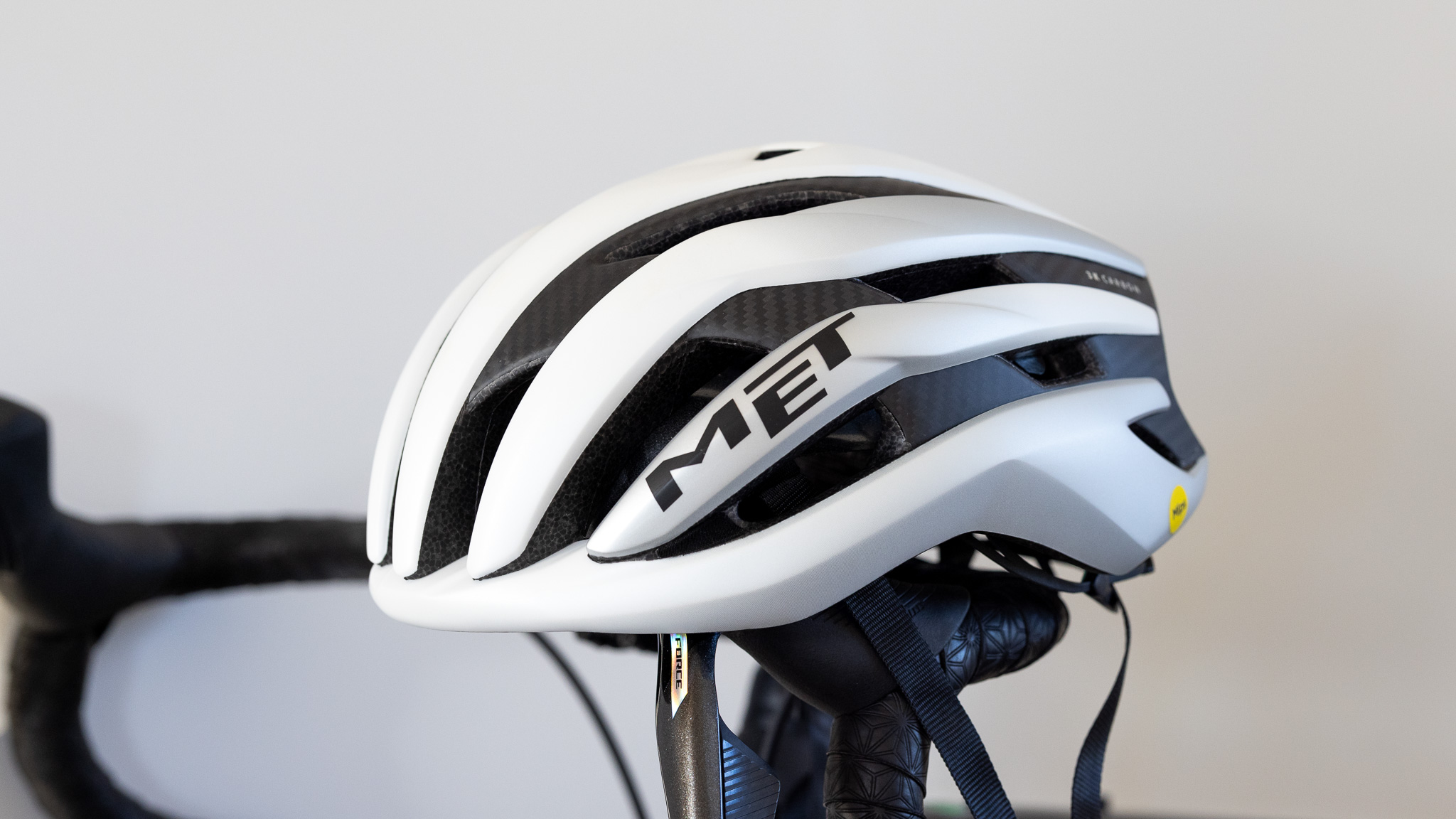The MET Trenta 3K Carbon MIPS helmet in white on bike handlebar close up details
