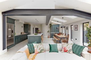 Open plan with steel bar, cream, grey and green island, dining table and walls