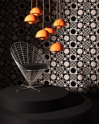 A Wire Cone chair and orange pendant lights by Verner Panton photographed with a black and white optical backdrop