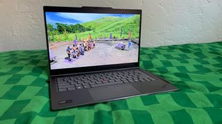 The Lenovo ThinkPad X1 2-in-1 Gen 9 sitting on a green blanket with CBS's Survivor on screen
