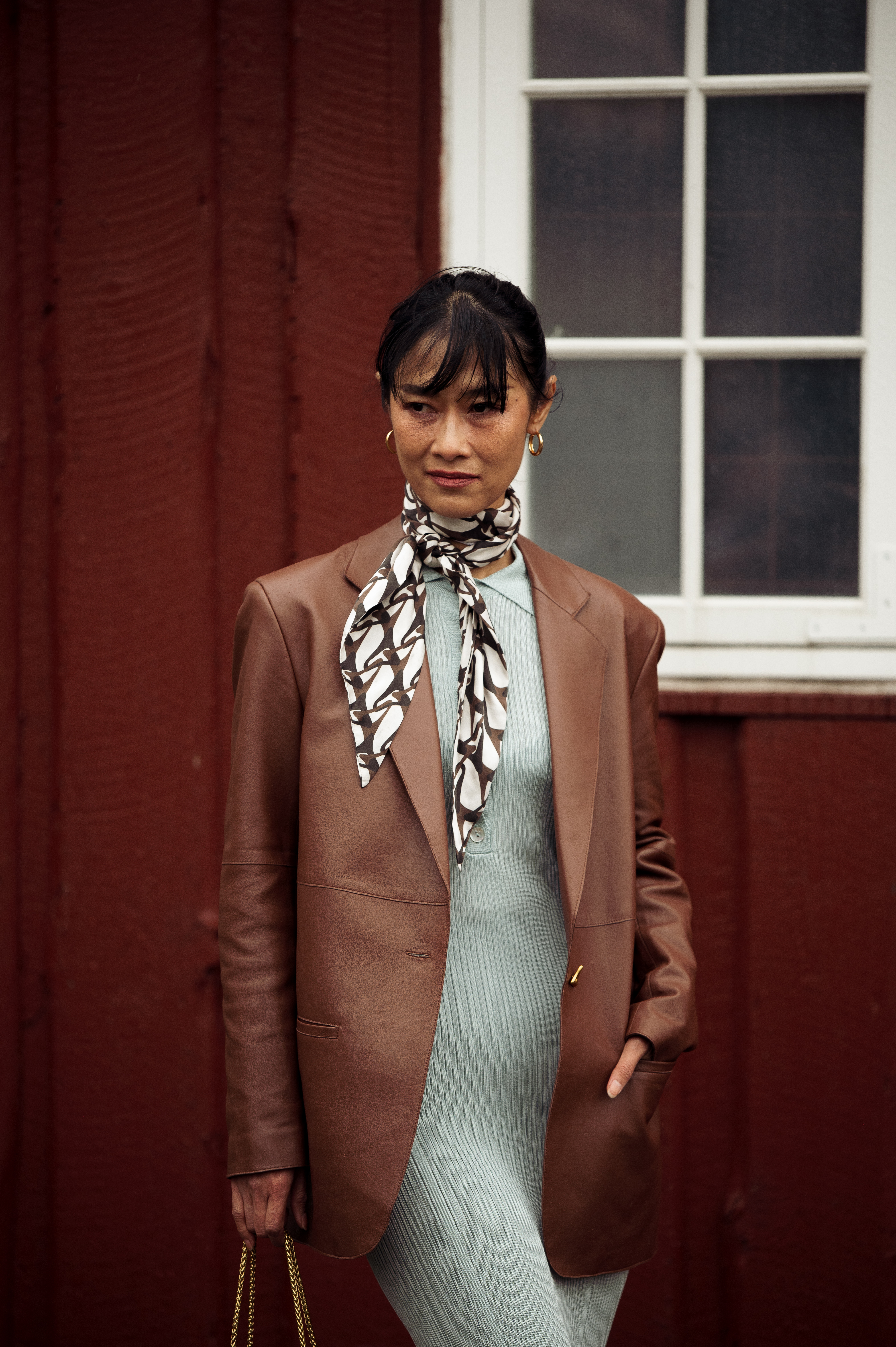 Pornwika Spiecker wears a mint dress, brown leather blazer, and silk neck scarf and black bag outside Aeron during the Copenhagen Fashion Week Autumn/Winter 2023 on January 31, 2023 in Copenhagen, Denmark. (