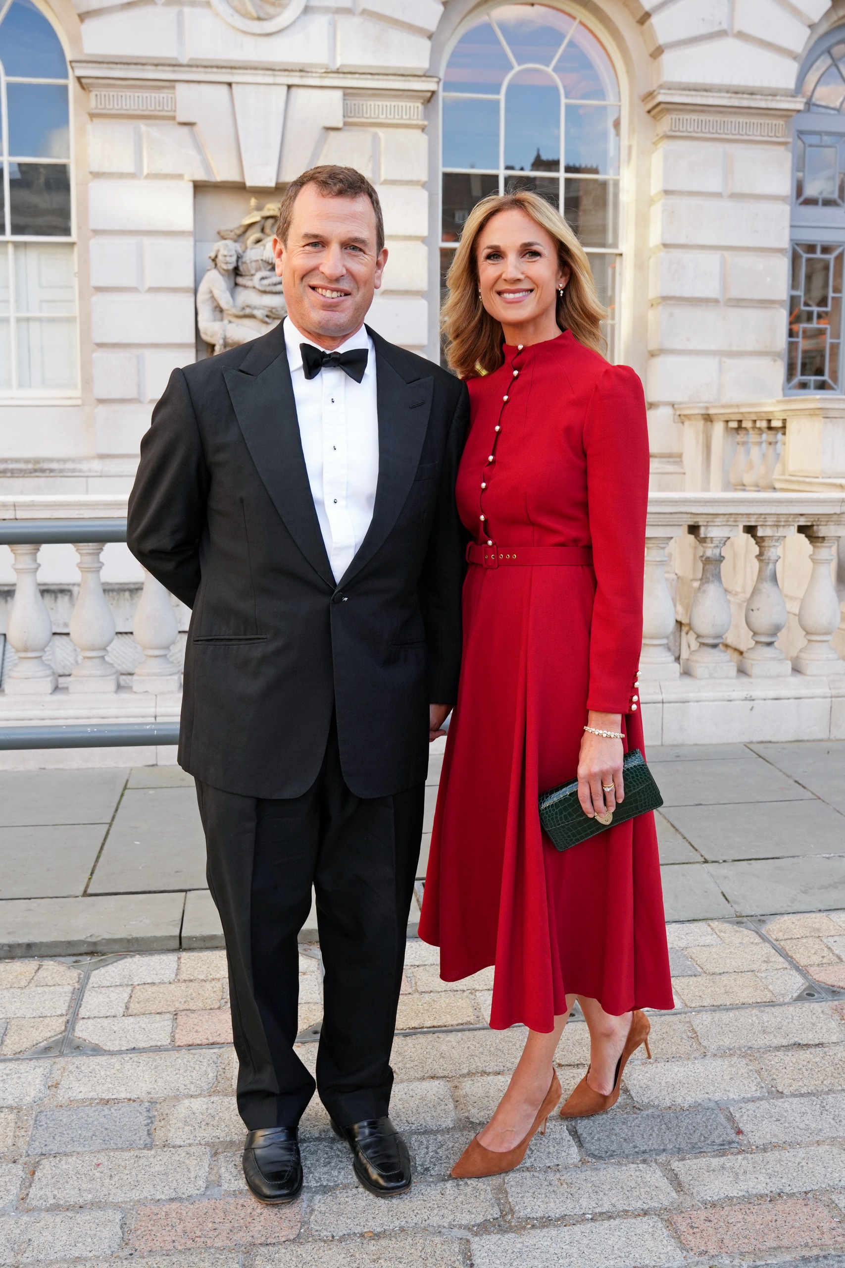 Peter Phillips ain a tux and Harriet Sperling wearing a red dress outside Somerset House