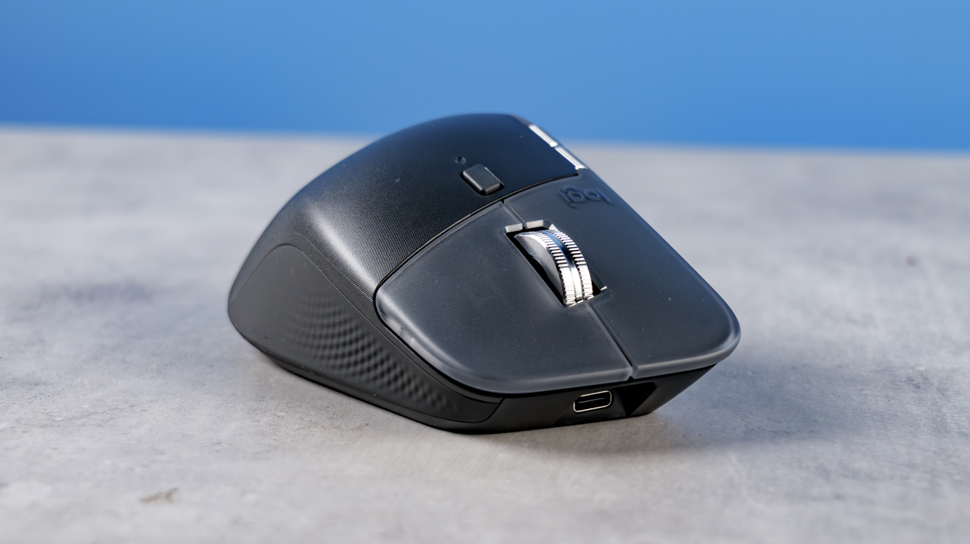 A photo of the Logitech MX Master 4 on a stone surface with a blue background