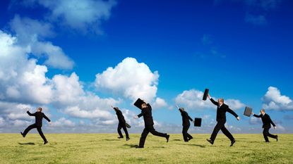 Men in suits run across a field.