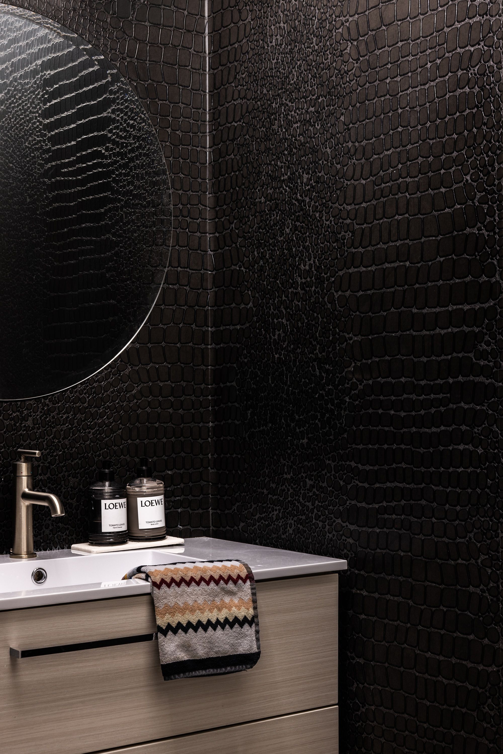 A small powder room with crocodile skin effect wallpaper
