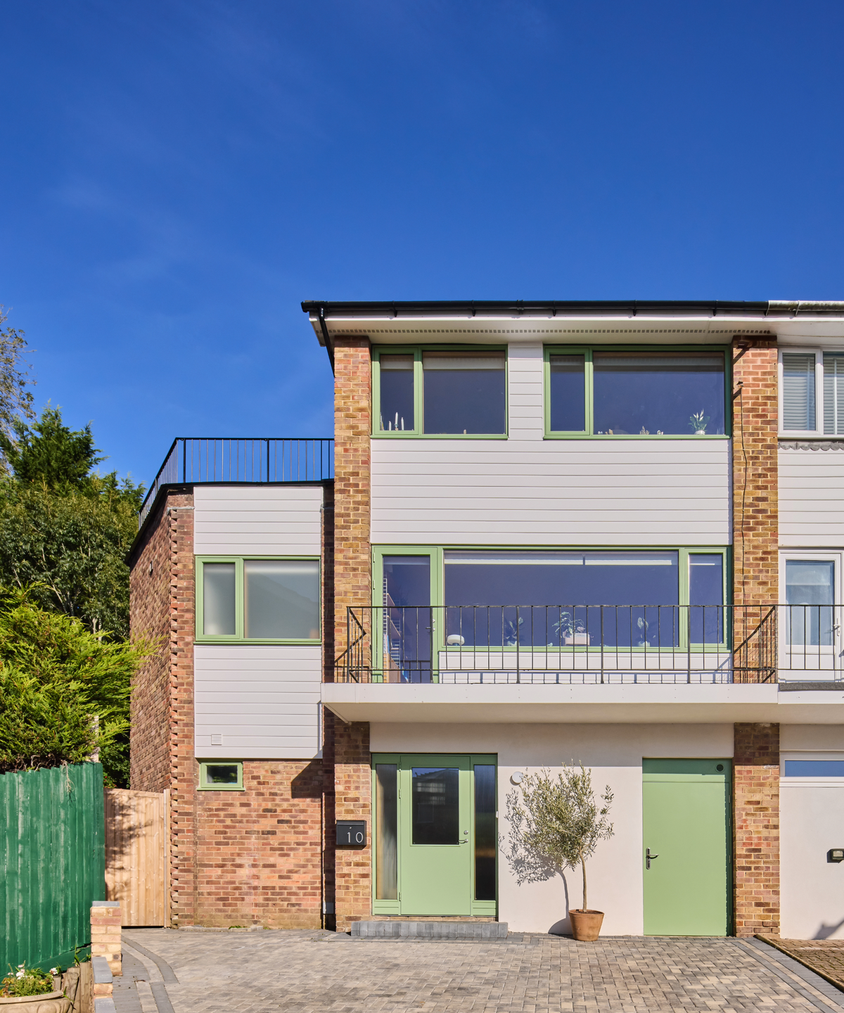 The front exterior of the house, featuring pastel green window trimmings and doors