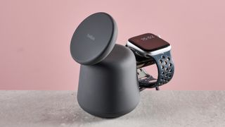 The phone charging pad of the 2-in-1 Belkin charger it standing up, and an Apple Watch can be seen charging on the rear charing module.