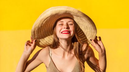 Girl wearing big summer hat and red lipstick - how to make makeup last in the heat