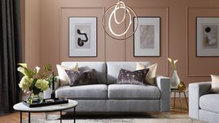 living room with soft teracotta colour panelled walls, grey sofa and pendant light