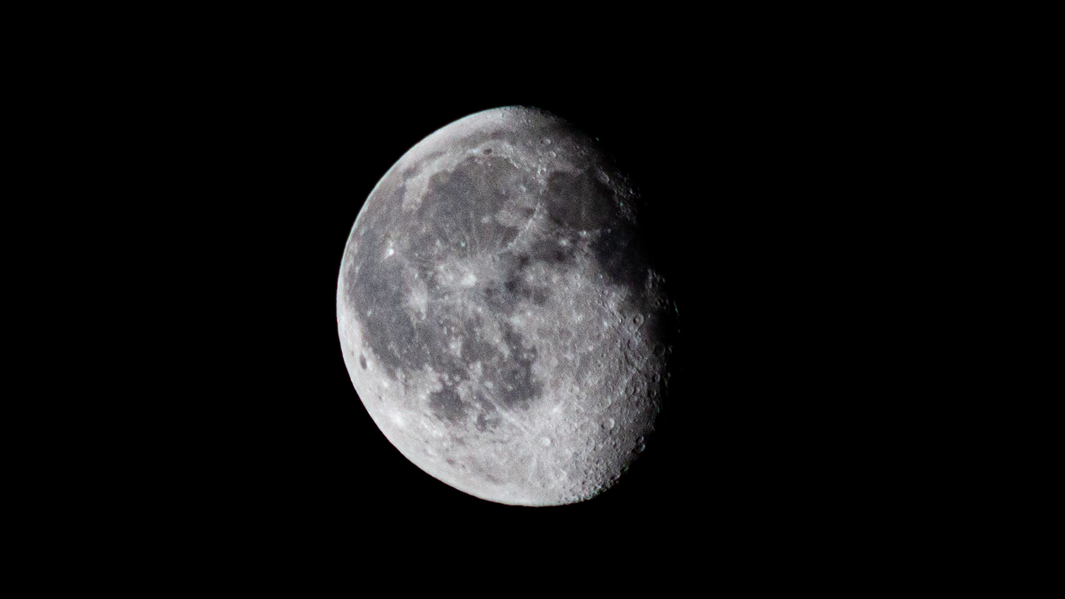 A large waning gibbous moon in the night sky with lunar seas and craters visible.