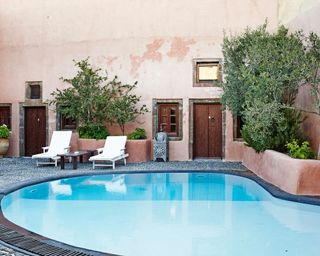 Raised garden bed ideas beside a swimming pool in a terracotta painted Mediterranean inspired courtyard garden.