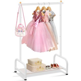 A white childrens clothing rail with hanging dresses, a pink rabbit handbag, and a shelf at the bottom with two patterned suitcases and two pairs of shoes