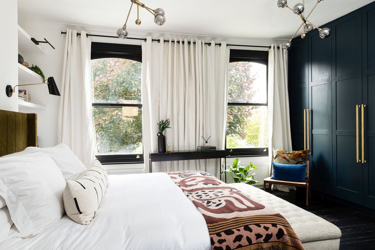 a bedroom with eyelet curtains on a rod