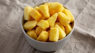 frozen pineapple in grey bowl on grey sheet