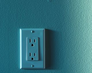 an aquamarine blue plug socket on a matching wall with a textured finish