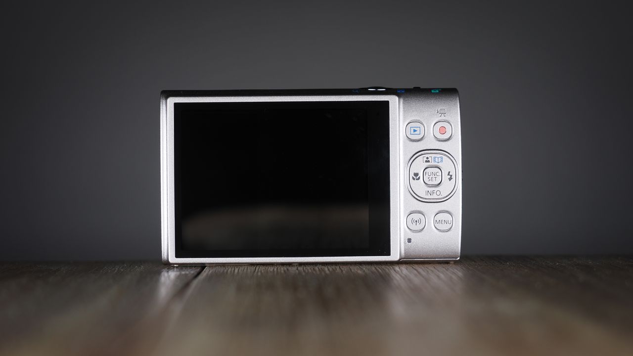 Canon Ixus 285 HS A on a wooden surface against a dark background