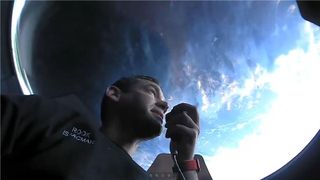 Inspiration4 mission commander Jared Isaacman speaks into a radio beneath the SpaceX's Dragon Crew Resilience's cupola, with Earth in the background