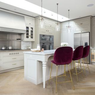 A modern kitchen with glam red velvet island seating at a white breakfast bar