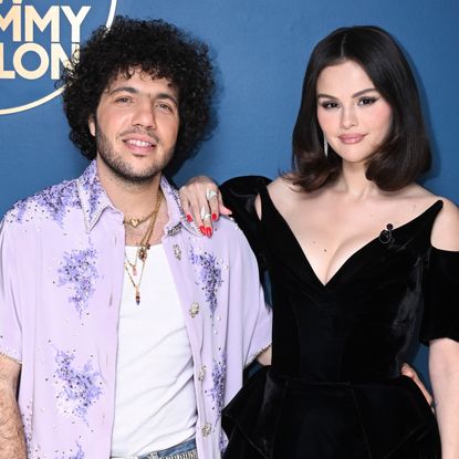 Benny Blanco in a purple shirt with a white tank top underneath and Selena Gomez in a black dress backstage at The Tonight Show in March 2025