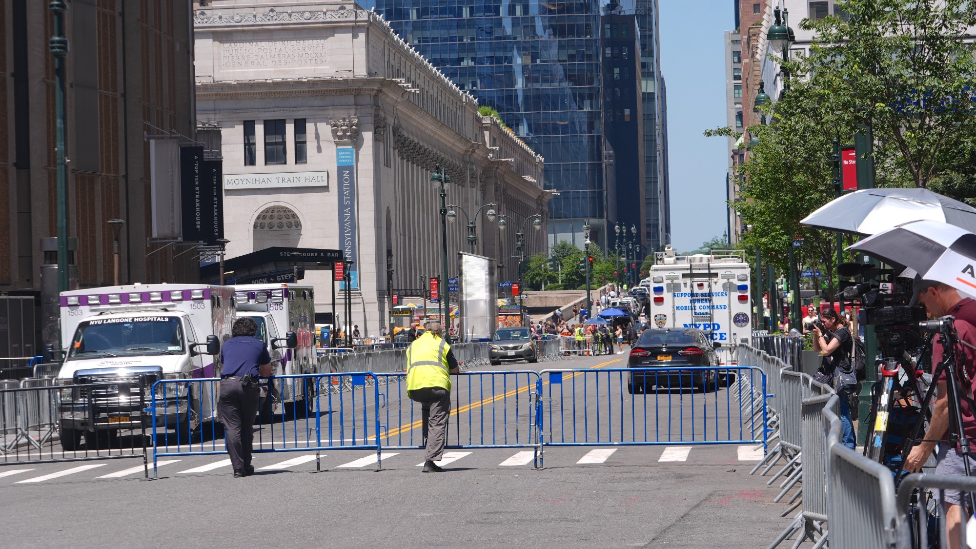 Security staff and emergency services man a roadblock in Midtown Manhattan, while press photographers look on