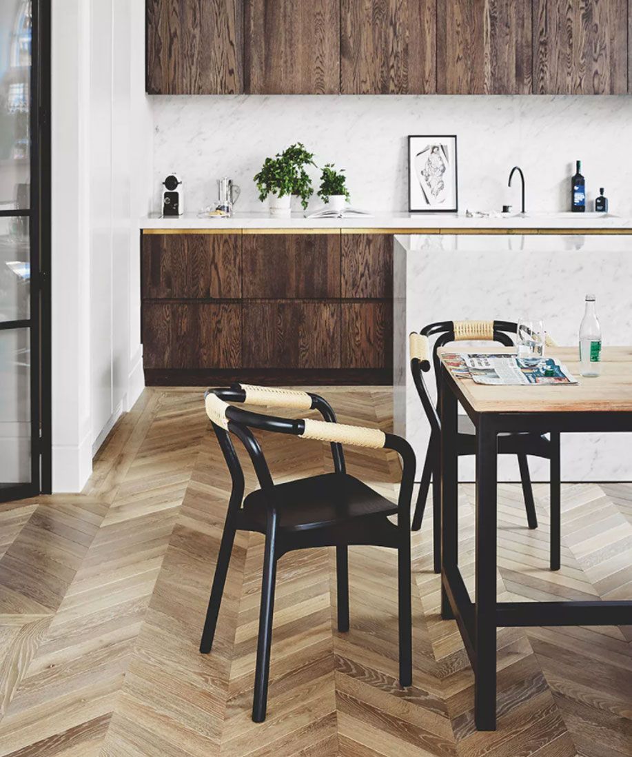 Kitchen flooring ideas illustrated by herringbone wood with black dining chairs.