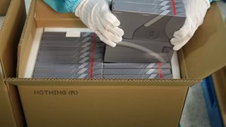Nothing products being loaded into a cardboard box, by a person wearing white gloves 