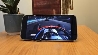 Apple iPhone 16 smartphone on wooden table showing F1 on screen