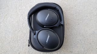 The Bose QuietComfort 45 headphones resting on their case on a gray floor