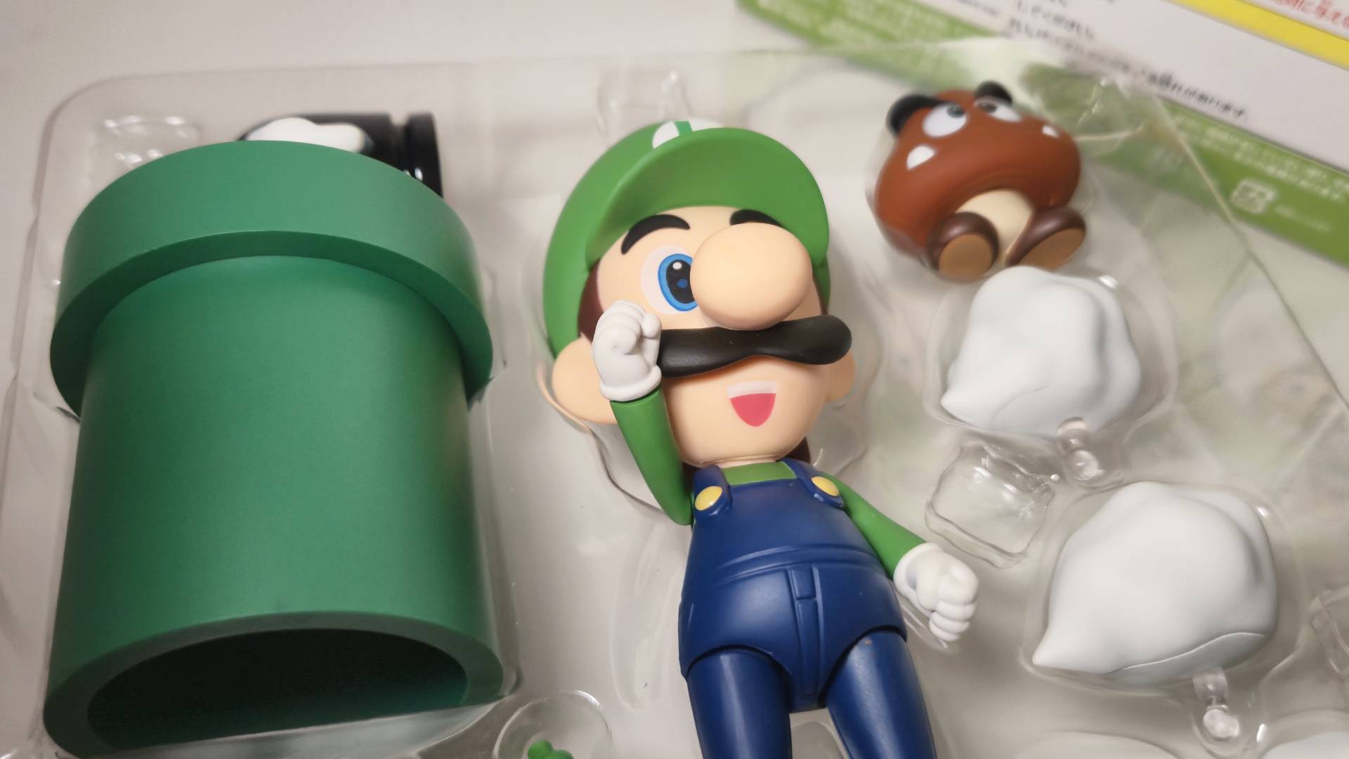 Photo of the Luigi Nendoroid figure in its packaging surrounded by accessories.