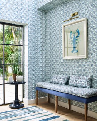 Blue and wooden bench against blue coral wallpaper with matching cushions on the bench