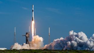 a black and white rocket launches into a blue sky