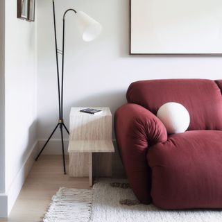 Red sofa with boucle cushion next to marble side table and contemporary style floor lamps