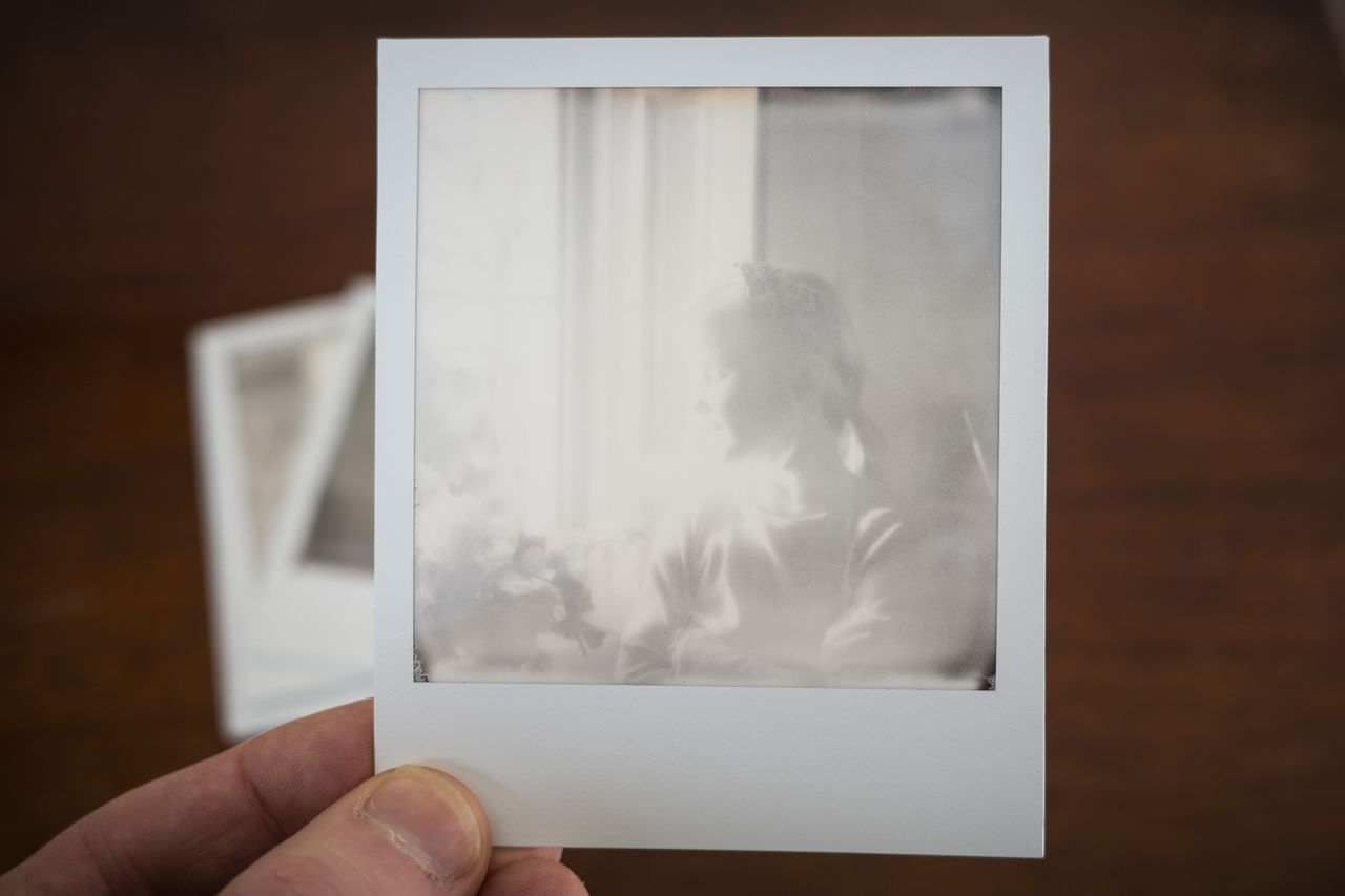 Polaroid SX70 instant print in the hand, black and white portrait