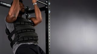 Strong athlete doing pull ups wearing a Mirafit weighted vest