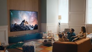 5 steg for en bedre LG OLED TV-opplevelse: LG G2 på en vegg i en stue mens en familie ser på fra sofaen