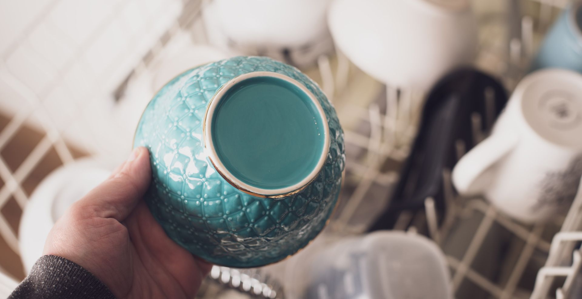 person loading a dishwasher to support cleaning a kitchen