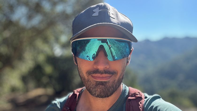 A selfie of the author wearing Oakley Meta Vanguard White/ Prizm Sapphire smart glasses with blurry trees behind him.
