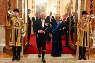 Queen Camilla wears a blue velvet gown with Queen Elizabeth's aquamarine ribbon tiara and matching earrings and a necklace