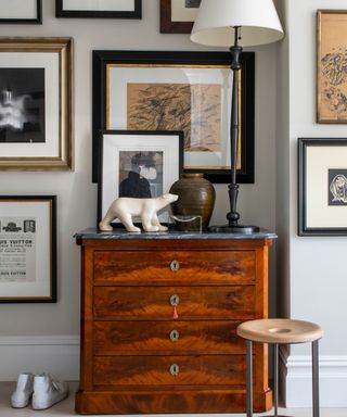 A vintage set of wooden drawers in front of a black and white gallery wall