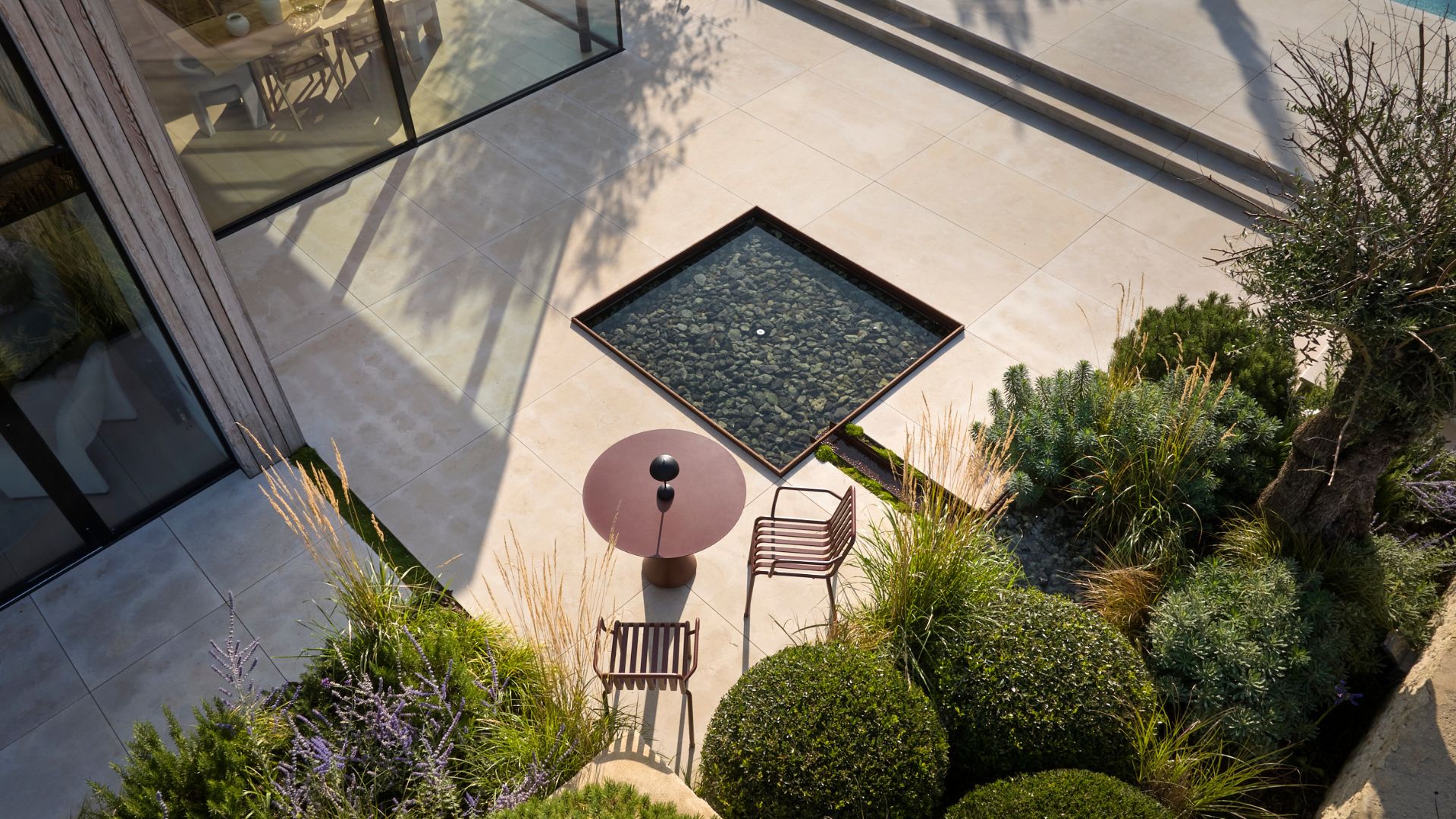 A square fountaine water feature in an outdoor living room by a garden