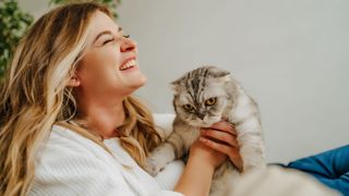 Woman laughing while holding cat