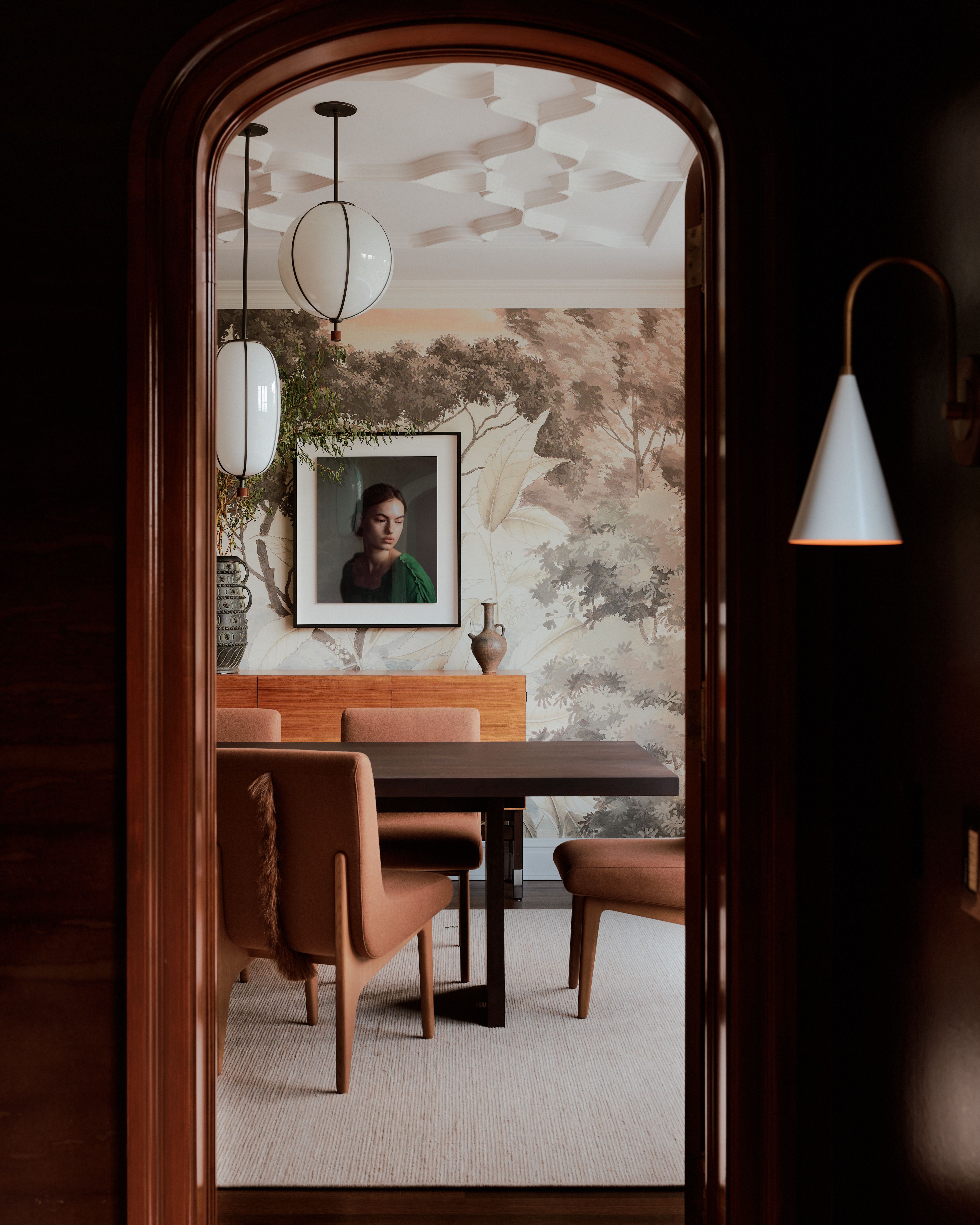Interior of a Tudor home with sleek wood floors and paneled walls, thriving plants, and sculptural decor.